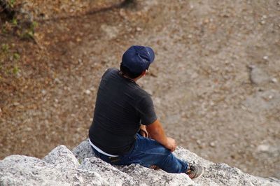 High angle view of man sitting on rock