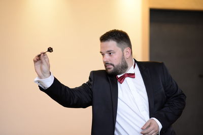 Groom aiming through dart against wall