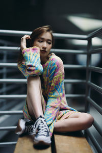 Portrait of young woman sitting on escalator