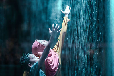 Mother with son enjoying rainfall at night