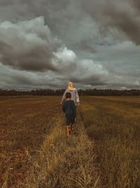 Full length of woman standing on field against sky