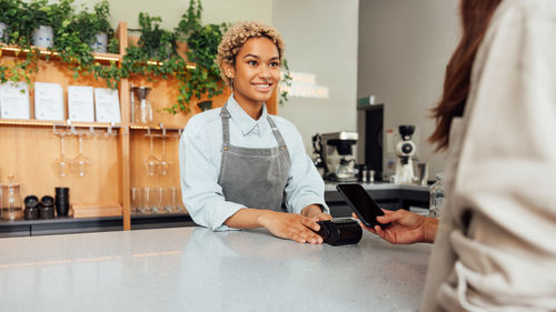 Portrait of young woman using mobile phone while standing in office