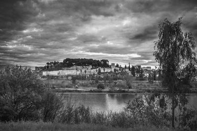 Scenic view of river by buildings against sky