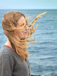 Woman with long hair standing against sea