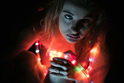 Close-up portrait of young woman with led lights