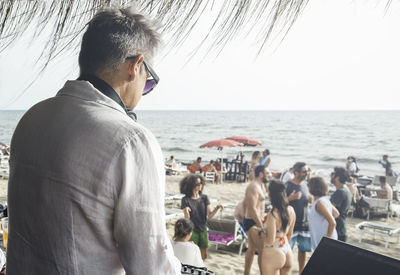 Rear view of people at beach against sky