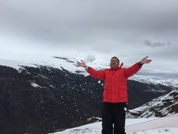 Full length of man standing on snow covered mountain against sky