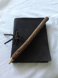High angle view of book and wooden pencil on tablecloth