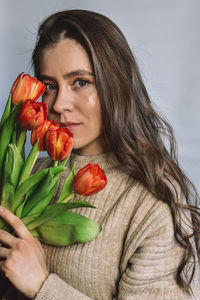 Portrait of smiling young woman holding flowers