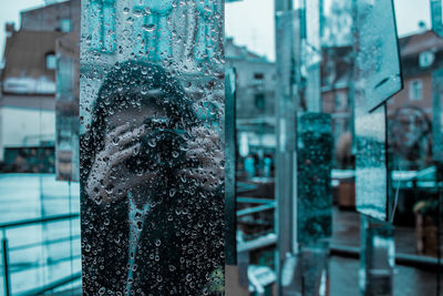 Woman photographing reflecting on wet glass