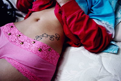 Midsection of sensuous woman lying on bed at home