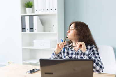 Young woman looking down while sitting on table