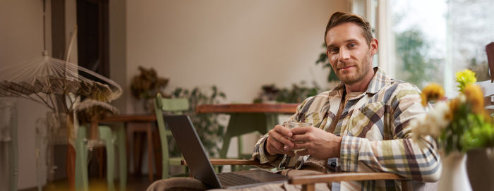 Side view of man using digital tablet while sitting at home