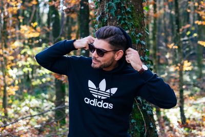 Young man wearing sunglasses standing in forest