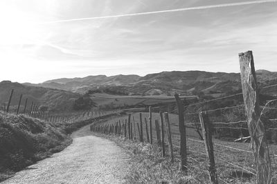 Wooden fence on field by mountains against sky