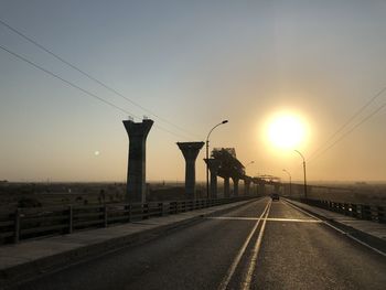 Bridge over road against sky during sunset