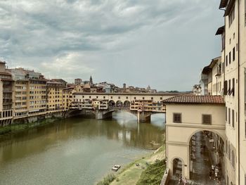 Bridge over river by buildings in town against sky