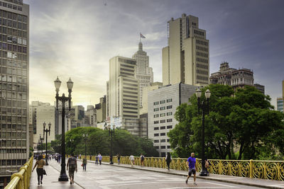 People on street amidst buildings in city against sky