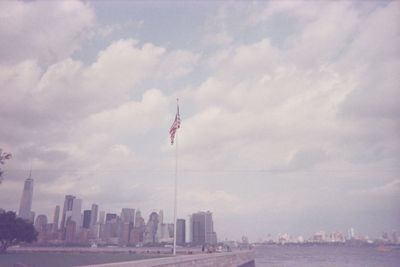 Low angle view of flag against sky in city