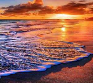 Scenic view of sea against dramatic sky during sunset