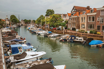 Wide canal with old buildings and moored boats at dordrecht. historic city with port in netherlands.