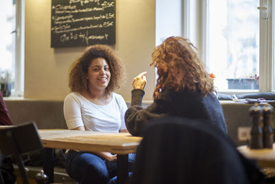 Friends talking while sitting at table in restaurant