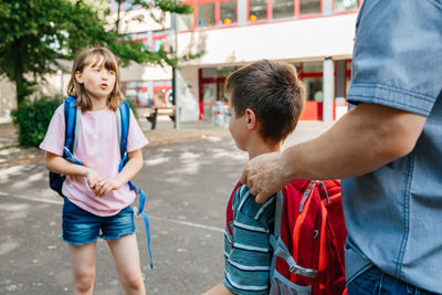 Back to school. a happy dad escorts his children, a boy and a girl, to school