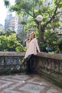 Portrait of woman standing by tree against plants