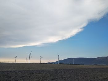 Wind turbines on field against sky