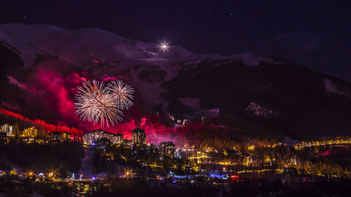 Firework display over illuminated cityscape at night