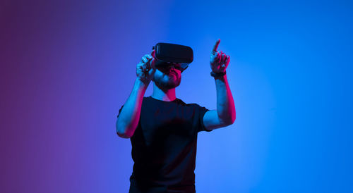 Rear view of man photographing against blue background