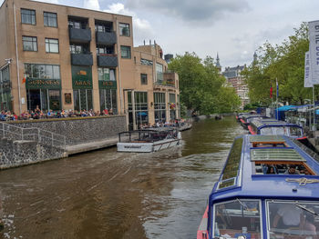 Boats moored on river in city against sky