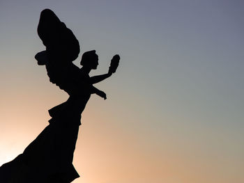 Low angle view of silhouette statue against sky during sunset