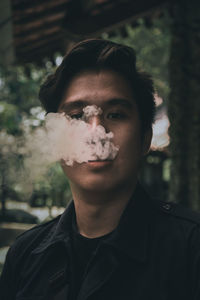 Portrait of young man emitting smoke