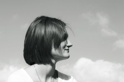 Woman looking away while standing against sky