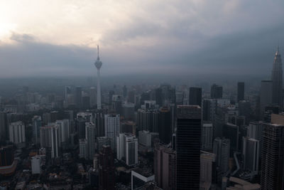 Aerial view of buildings in city against cloudy sky