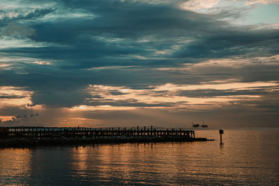 Pier over sea against sky at sunset