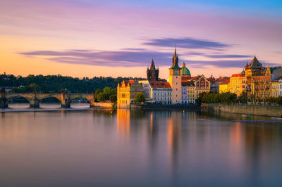 River amidst buildings against sky during sunset