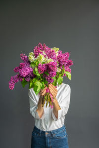 Midsection of person holding purple flowering plant against black background