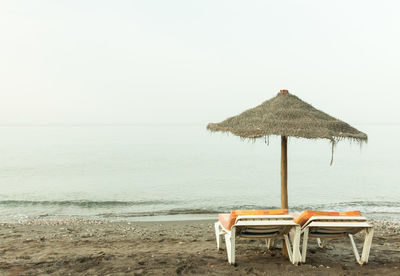 Deck chairs on beach against clear sky