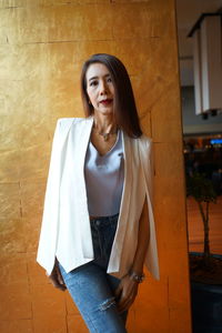 Portrait of well-dressed woman standing against wall