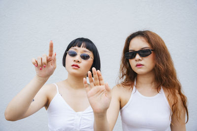 Lesbian couple gesturing while standing against wall outdoors