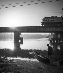 Man on bridge over river against sky
