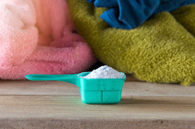 Laundry detergent in plastic spoon on table