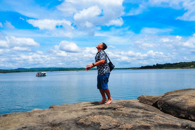 Full length of man standing on rock against sky