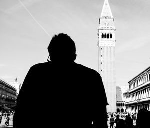 Rear view of silhouette man standing in city against sky