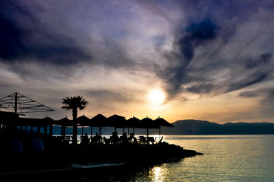 Silhouette swimming pool by sea against sky during sunset