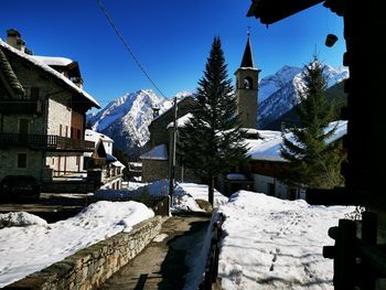 Snow covered houses by buildings against sky