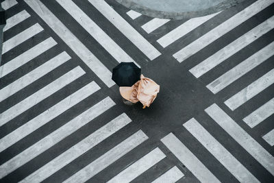 Woman dancing in a zebra crossing with a dress and an umbrella