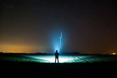 Silhouette man standing on field against sky at night